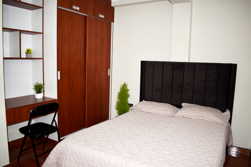 Dormitorio amoblado con una cama de dos plazas con ropero empotrado y una mesita de estudio del departamento amoblado