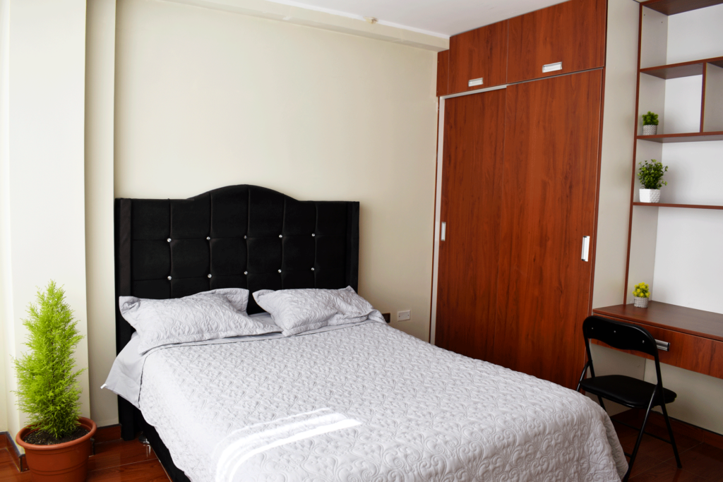 Dormitorio amoblado con una cama de dos plazas con ropero empotrado y una mesita de estudio del departamento amoblado
